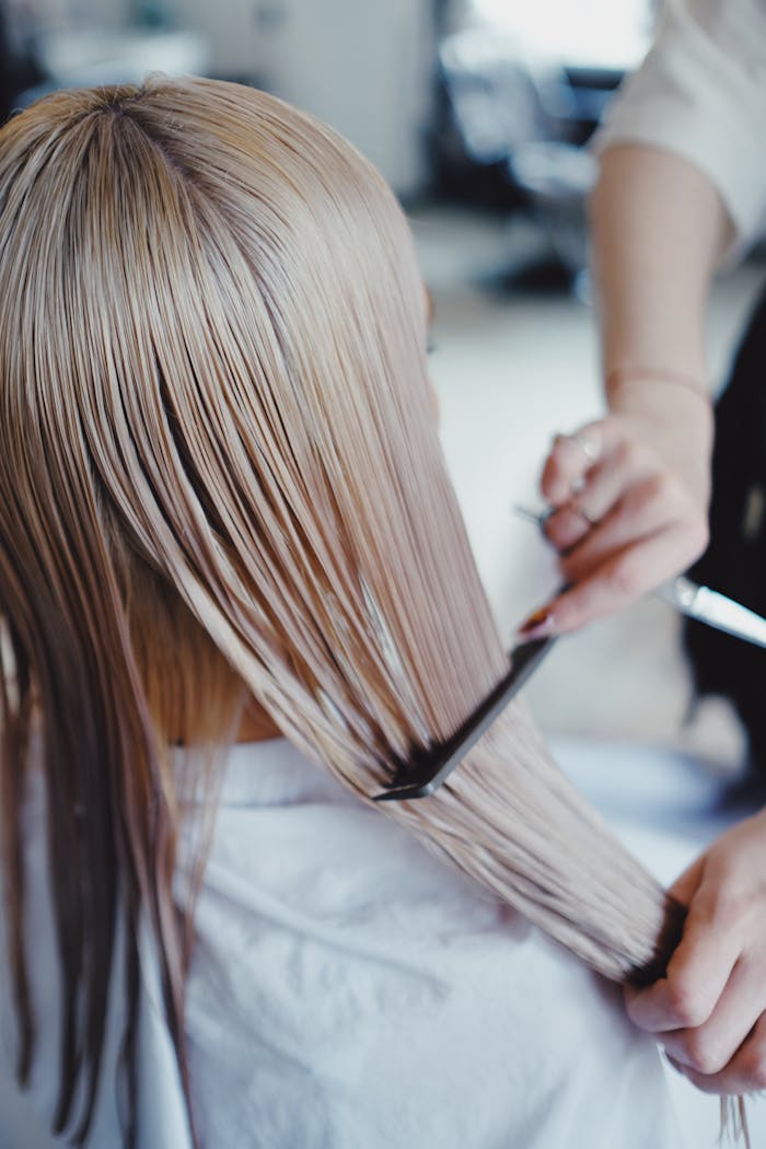 Mastering the First Impression: Your intriguing post title goes here Close-up of a hairstylist arranging long, straight blonde hair in a salon environment.